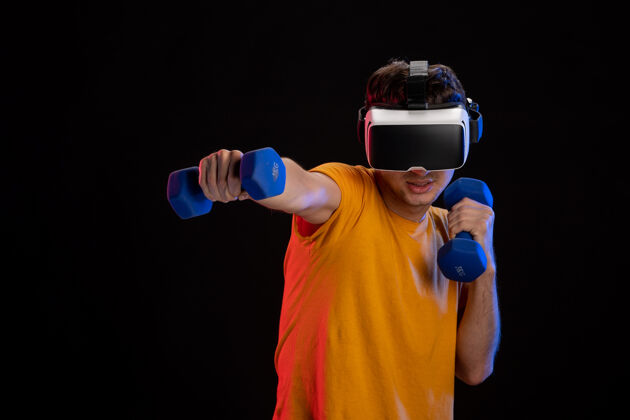 游戏年轻男性在黑暗的表面上玩哑铃虚拟现实人现实黑暗