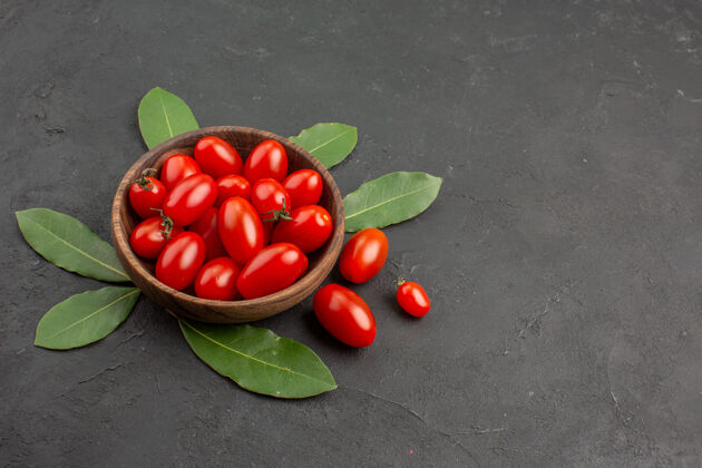 可食用水果底视图一碗樱桃番茄和月桂叶放在黑色的桌子上 留有复印空间西红柿底部水果