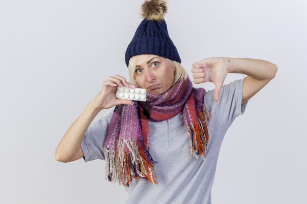 金发年轻的金发病斯拉夫女人戴着冬天的帽子和围巾不愉快帽子拇指
