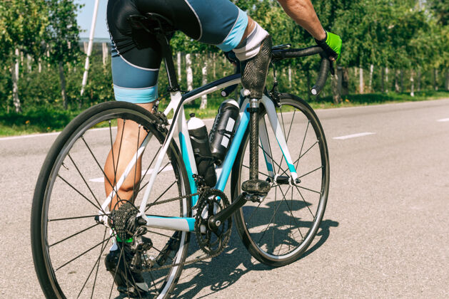 问题残疾运动员或截肢者在阳光明媚的夏日进行自行车训练专业男性运动员带假肢在户外练习残疾运动和健康的生活方式理念腿截肢锻炼