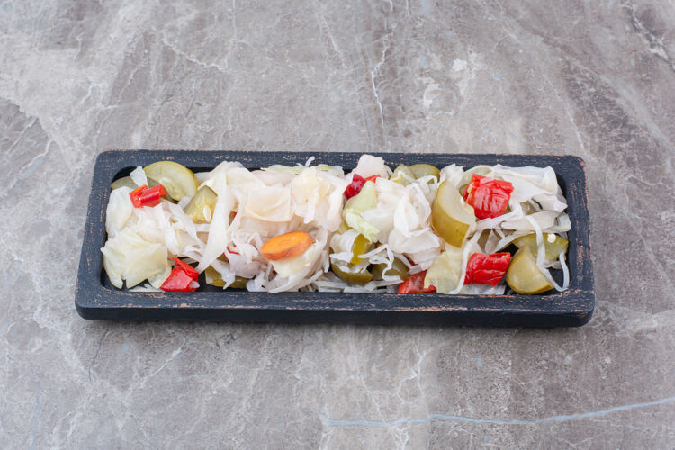 食物各种各样的腌菜碎放在深色的盘子里泡菜卷心菜胡椒