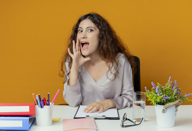 年轻年轻漂亮的女上班族坐在办公桌旁 拿着办公工具低语着办公桌办公室橙色