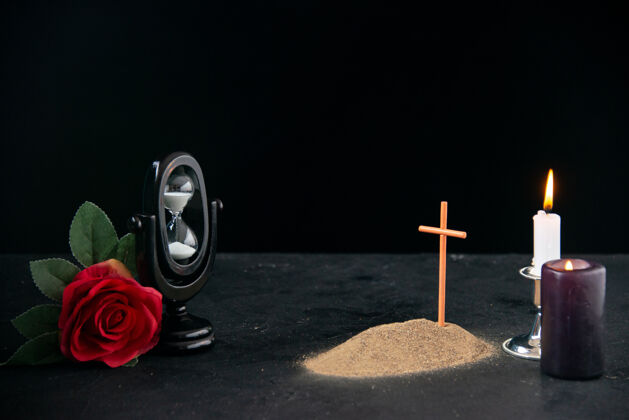 俱乐部一个小小的坟墓 在黑暗的表面上用蜡烛和鲜花作为记忆花蜡烛表面