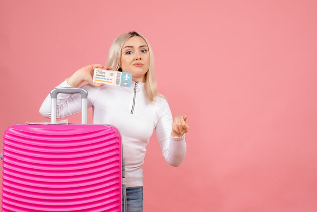 女士正面图年轻女士站在粉红色手提箱后面 手里拿着机票成人休闲手提箱