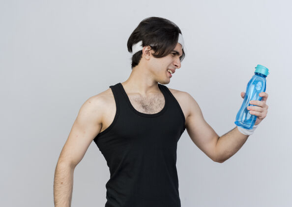 运动装一个穿着运动服 戴着头巾 手里拿着一瓶水的年轻人站在白色的墙上 看着它困惑的样子运动姿势头带