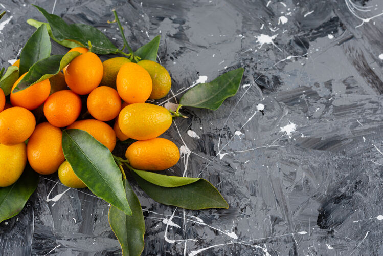 美味一堆成熟的金橘 大理石表面有绿叶水果美食明亮