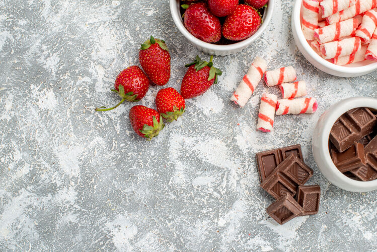 壁板上半视图碗与草莓巧克力糖果和一些草莓巧克力糖果在灰白色马赛克地面右侧可食用水果浆果水果