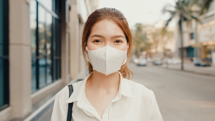 肖像成功的亚洲年轻女商人穿着时尚的办公服 戴着医用面罩 在街上微笑着医药脸日本人