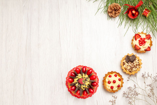 树叶顶视图浆果蛋糕馅饼和松树叶与圣诞玩具在白色木桌的右侧桌子浆果蛋糕馅饼