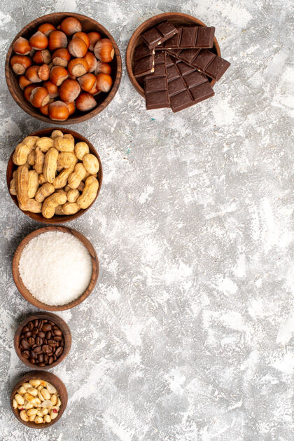 配料白色表面上有榛子和花生的巧克力棒俯视图坚果种子咖啡