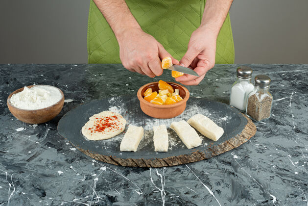切男厨师在大理石桌上把橘子切成块碗刀围裙