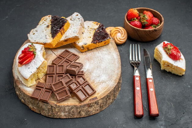 背景前视图蛋糕片与巧克力棒和草莓灰色背景餐厅奶酪抹刀