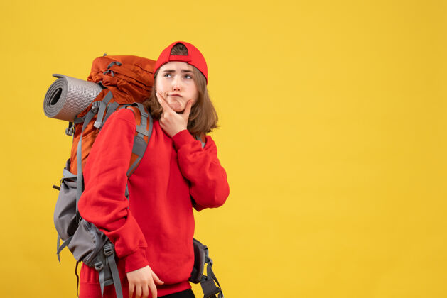 前面正面图：体贴的旅行者 穿着红色背包的女人站在黄色的墙上成人站背包