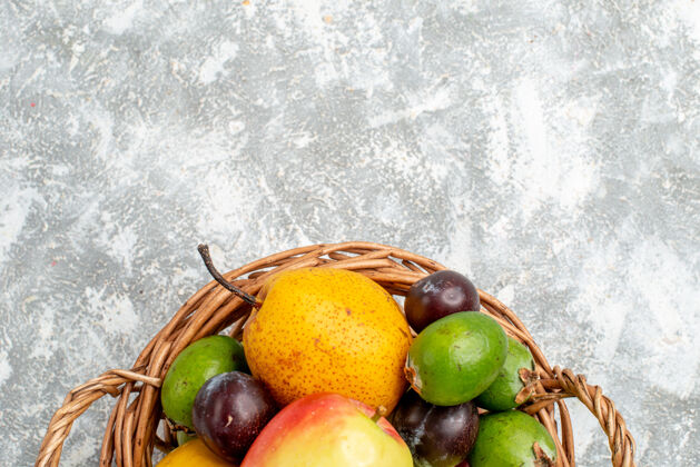 灰上半部分查看塑料柳条篮与苹果梨 李子和柿子在灰色的桌子上与自由空间橘子健康柠檬