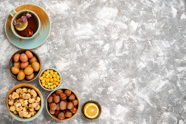 白色表面上有坚果和糖果的茶杯俯视图茶早餐坚果