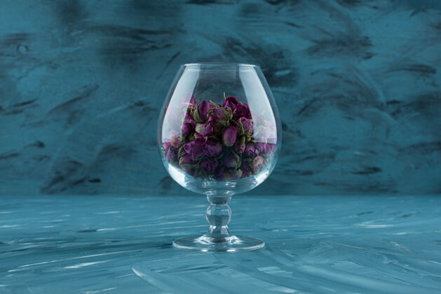 花瓣一杯干紫色玫瑰放在蓝色的表面上自然粉红花蕾