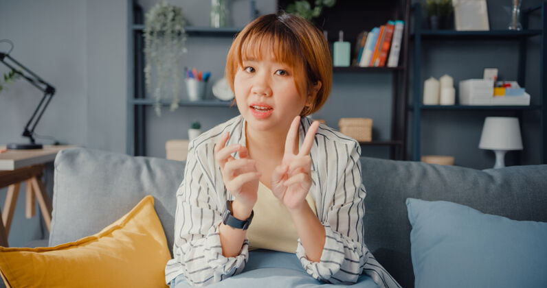 访谈亚洲女商人在起居室用笔记本电脑与同事谈论视频通话计划年轻人工作房子