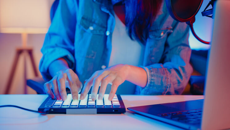 房子特写快乐的亚洲女孩dj使用启动板合成器键盘播放广播音乐