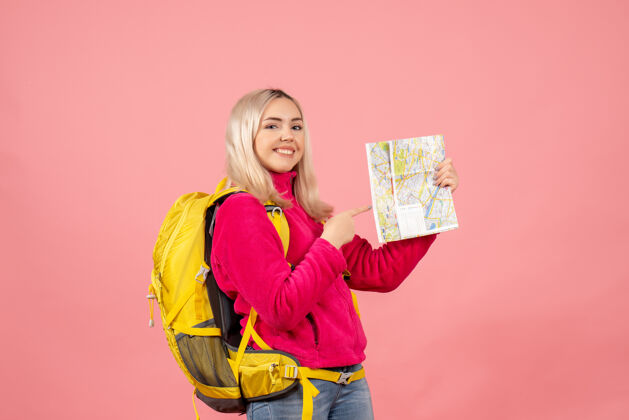 微笑正面图微笑的女旅行者 背着黄色背包 指着地图女士前面快乐