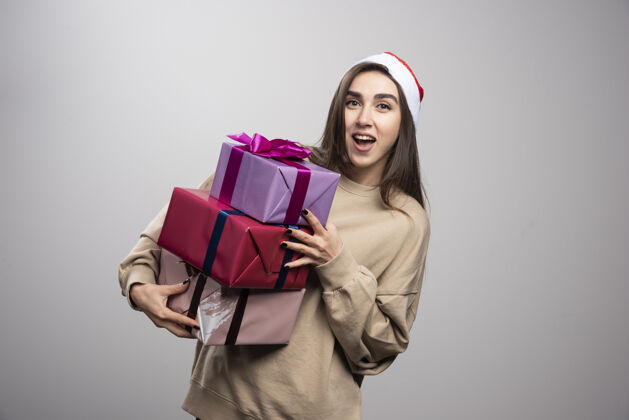 站着年轻女子手里拿着三盒圣诞礼物年轻红色兴奋