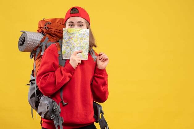 成人正面图漂亮的女旅行者背着背包把旅游地图举到脸上封面面具手持
