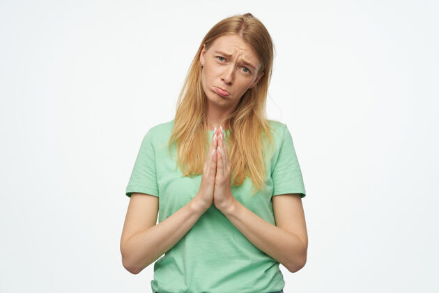 裤子年轻的金发女郎 穿着绿色t恤 手保持祈祷姿势 祈祷考试取得好成绩时尚发型祈祷