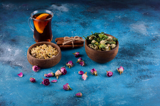健康蓝色桌子上放一杯热茶和干花香草药食物