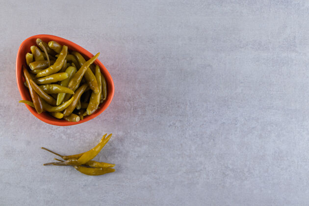 食物石桌上摆着一碗桔黄色的泡椒腌菜咸的辣椒