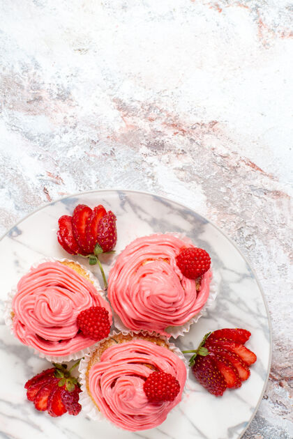 饼干白色表面上有新鲜的红色草莓的粉色草莓蛋糕俯视图可食用水果新鲜草莓