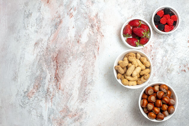 大理石白色表面上有新鲜草莓的花生和榛子的顶视图浆果面包坚果