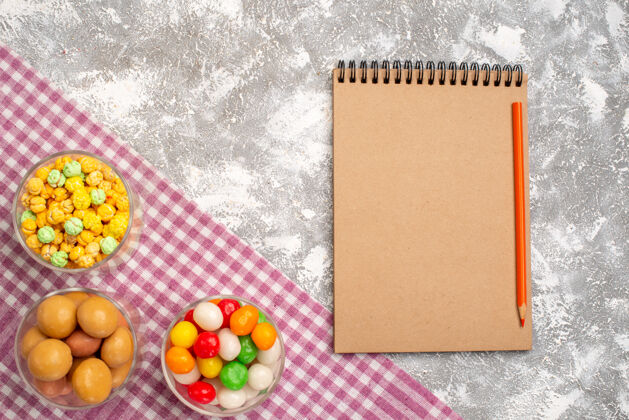 笔记本不同糖果的顶视图在眼镜内 白色表面上有记事本记事本书写工具空白