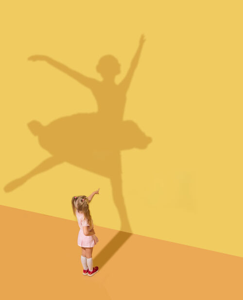 事业迎接未来童年和梦想的概念概念形象与孩子和阴影在黄色的工作室墙上小女孩想成为芭蕾舞演员 芭蕾舞演员 艺术家和建立一个事业点成功芭蕾舞演员