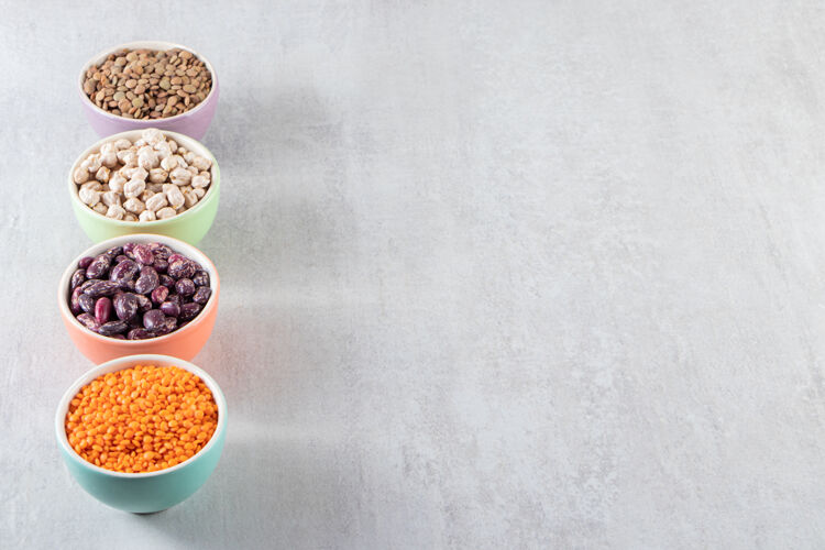 新鲜五颜六色的碗装满了生扁豆 豌豆和豆子放在石头表面蔬菜种子营养