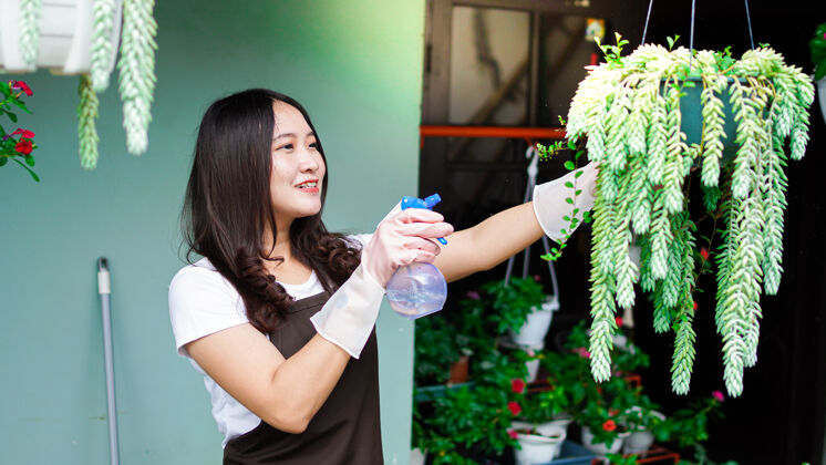 植物学亚洲女人在家花园浇花乡村浇水罐工作