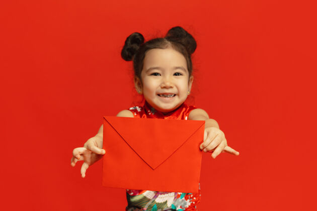 女性拿着红包 看起来很开心 微笑着中国新年快乐2020亚洲可爱的小女孩隔离在红色背景的传统服装庆祝 人类的情感 节日复制空间旗袍季节火花