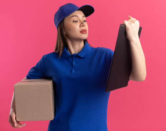 自信穿着制服的自信漂亮的女送货员拿着名片盒 看着粉色的剪贴板女人剪贴板送货