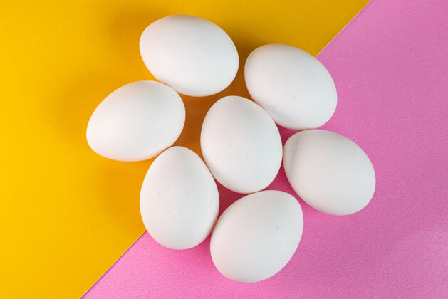 特写蛋在黄色和粉色的表面有机极简鸡蛋