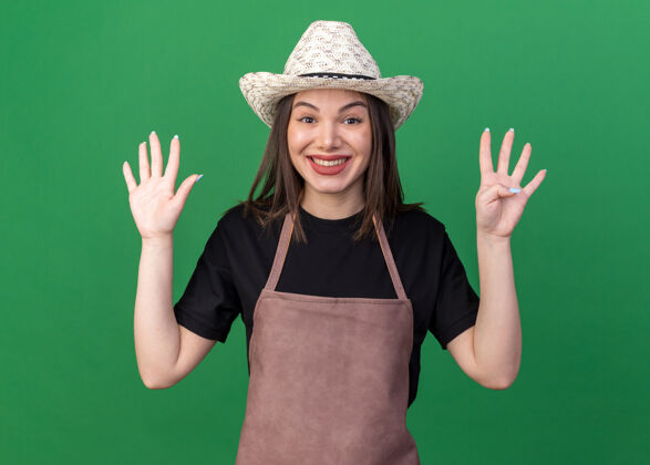园艺笑容可掬的白人女园丁戴着园艺帽 用手指在果岭上打九个手势帽子漂亮手指
