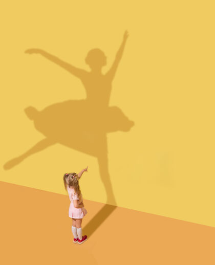 事业迎接未来童年和梦想的概念概念形象与孩子和阴影在黄色的工作室墙上小女孩想成为芭蕾舞演员 芭蕾舞演员 艺术家和建立一个事业点成功芭蕾舞演员
