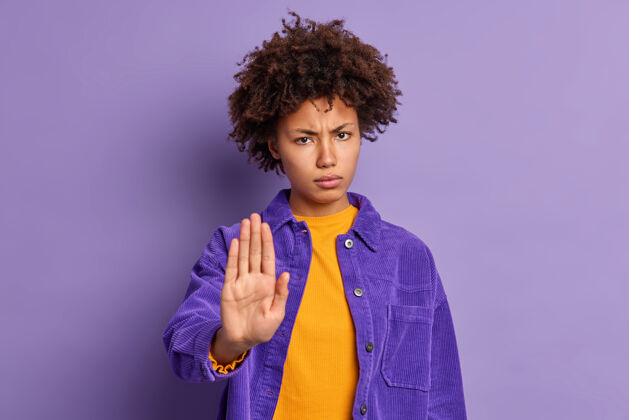 严重严重恼怒的黑皮肤美国黑人妇女保持手掌在停止手势要求不要打扰她的样子愤怒地穿紫色夹克表示限制或否认请不要靠近紫色美丽肖像