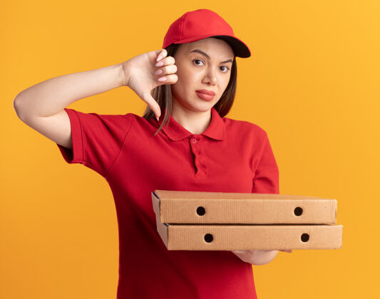 盒子一个穿着制服的漂亮女送货员大拇指朝下 手里拿着橘黄色的披萨盒女人橘子拇指