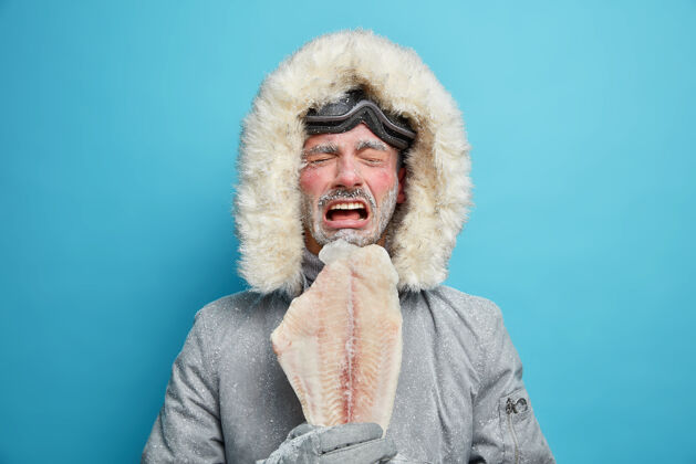 活动不高兴的北极人在严寒的天气里被霜冻覆盖 寒冷的气候和天气使北方的鱼类生活在冰冻之中男爱斯基摩人穿着外套极限冒险红色