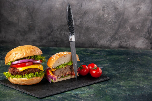 右全切各种美味的三明治和西红柿的俯视图 在黑色托盘的右侧 用干刀在深色混合色表面茎顶刀片