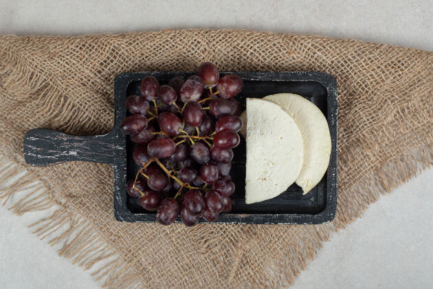 美味新鲜的红葡萄和白奶酪放在黑板上成熟配料一餐