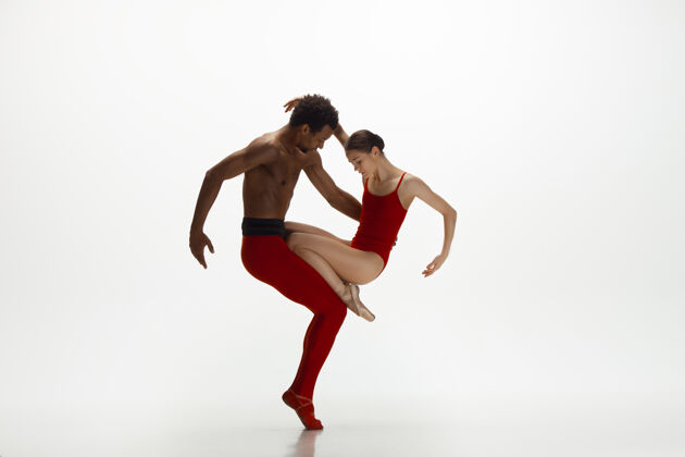 移动优雅的经典芭蕾舞者在白色的工作室背景上独立地跳舞一对穿着鲜红衣服的舞者就像是酒和牛奶的结合优雅 艺术家 动作 动作的概念经典体操优雅