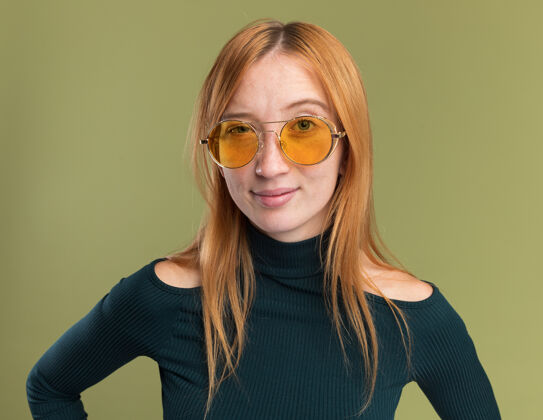 太阳自信的年轻红发姜女 戴着墨镜 满脸雀斑 看着橄榄绿的相机相机眼镜绿色