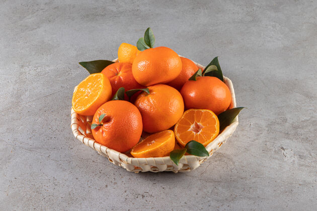 水果成熟的柑桔叶子放在柳条篮子里放在石头表面新鲜切片叶子