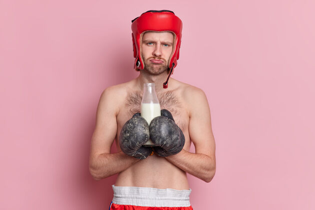 力量赤膊男拳击手有不悦的表情拿着奶瓶戴着运动手套训练后感觉很累不满意蛋白质白种人
