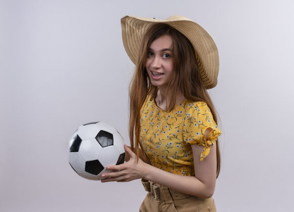 印象印象深刻的年轻女孩戴着帽子拿着足球在孤立的白色空间年轻女孩穿着