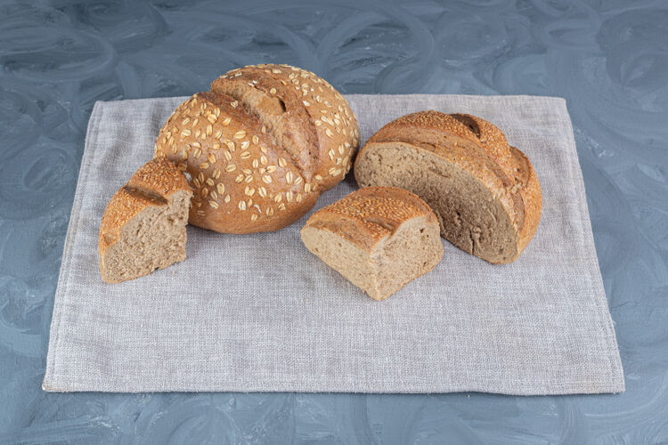 芝麻整条面包和切片面包捆在大理石桌上的毛巾上好吃的好吃的烤面包
